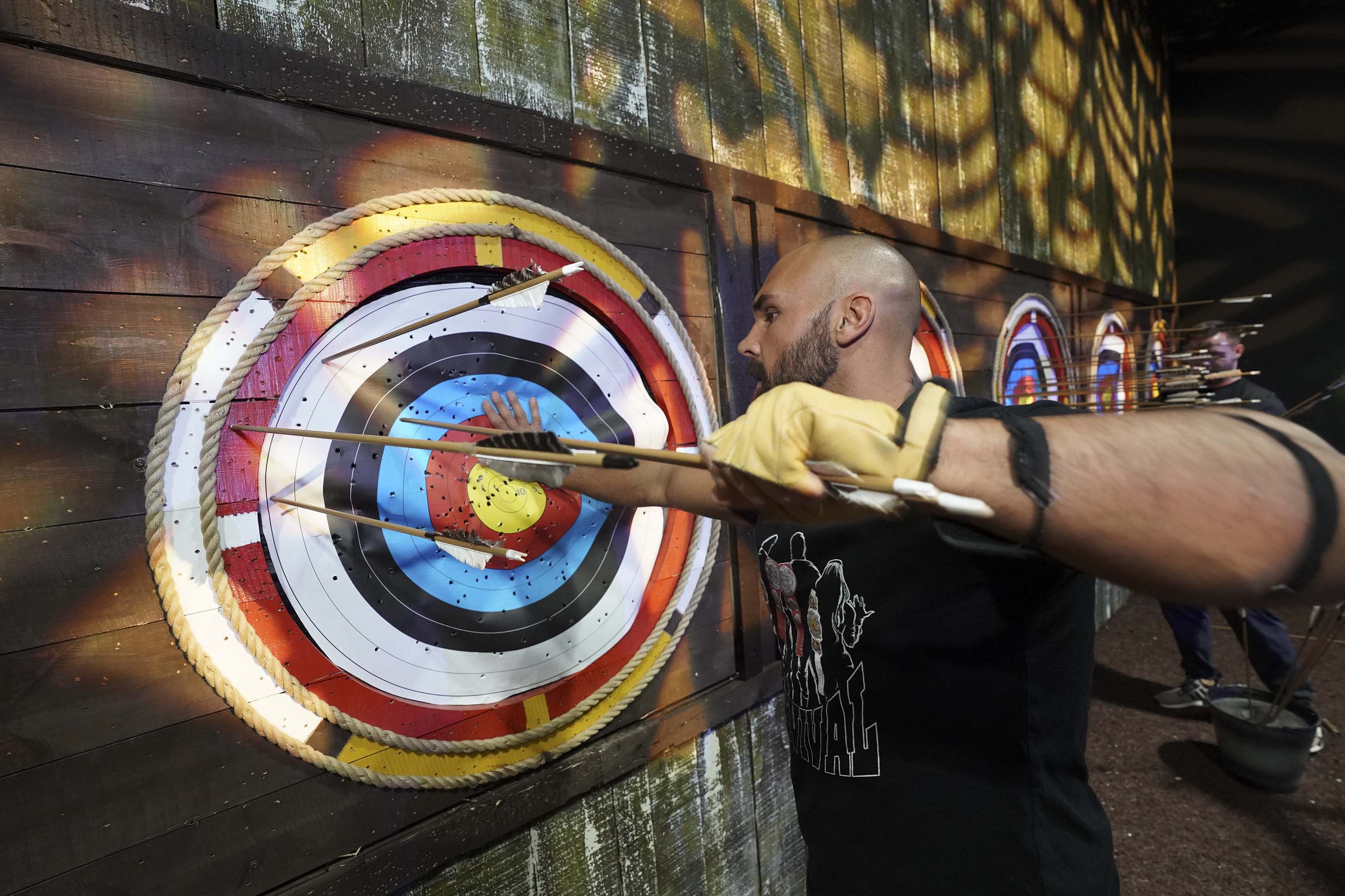 Man next to target full of arrows on Archery range at The Bear Grylls Adventure 