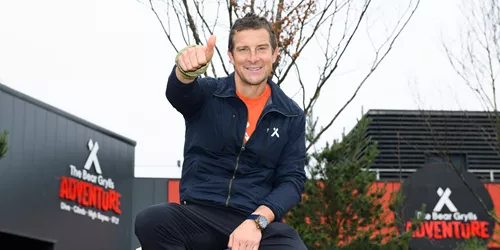 Bear Grylls gives thumbs up outside The Bear Grylls Adventure