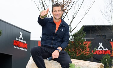 Bear Grylls gives thumbs up outside The Bear Grylls Adventure