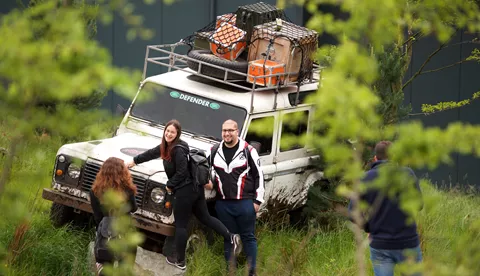 Family pose with themed Land Rover outside The Bear Grylls Adventure attraction main entrance