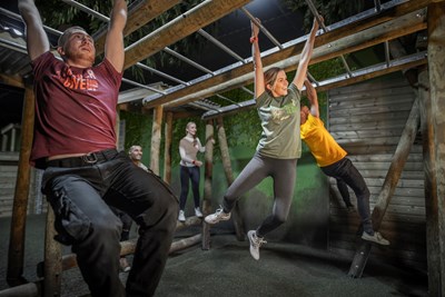 Group of friends on monkey bars on Assault Course at The Bear Grylls Adventure