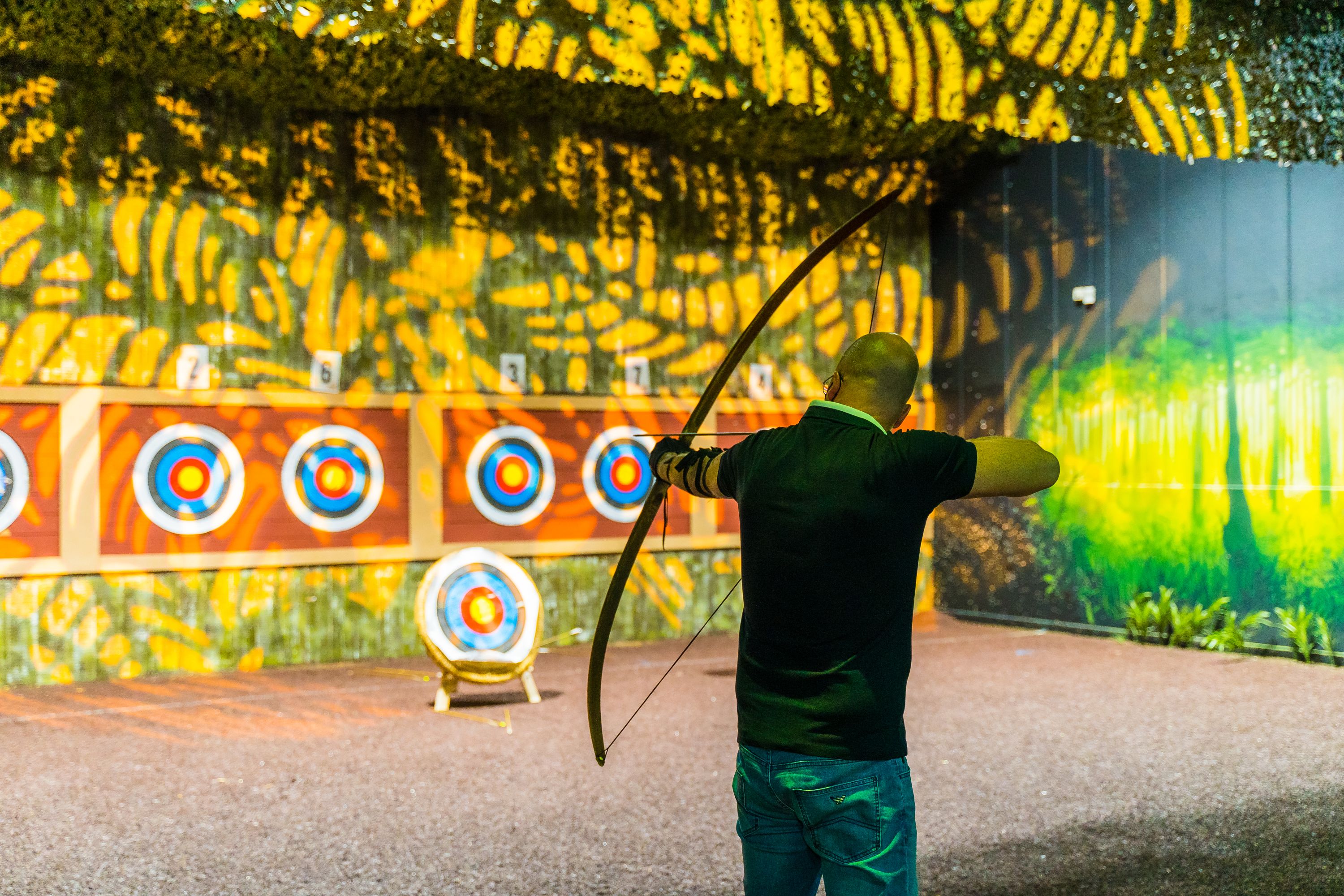 Man takes aim at target on archery range at The Bear Grylls Adventure